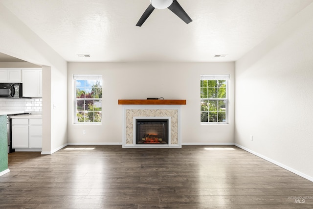 942 S Stibnite Pl, Kuna, ID 83634 - unfurnished living room with ceiling fan, a warm lit fireplace, dark wood-style flooring, and baseboards