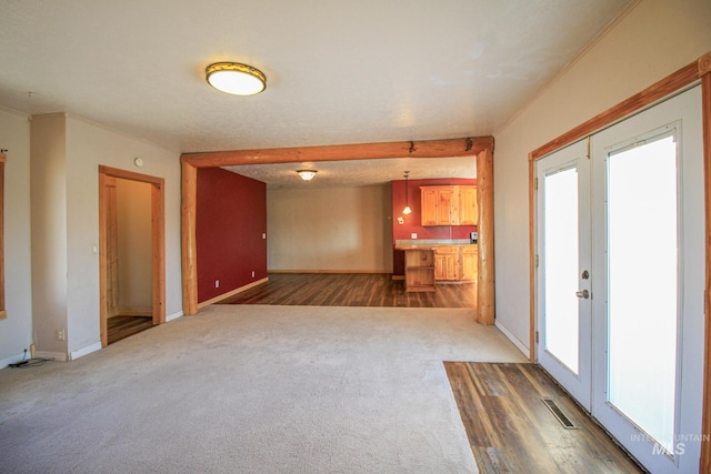 unfurnished living room with dark carpet and french doors