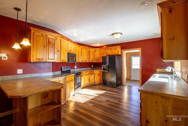 kitchen featuring sink, dark wood-type flooring, hanging light fixtures, black appliances, and kitchen peninsula