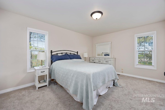 bedroom featuring light carpet, baseboards, and multiple windows