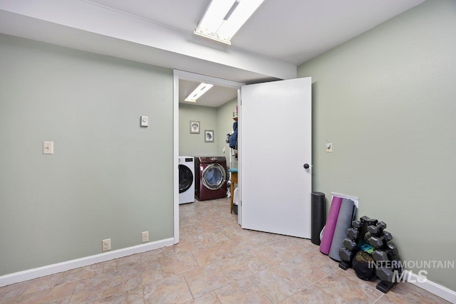 clothes washing area with washing machine and dryer, baseboards, and laundry area