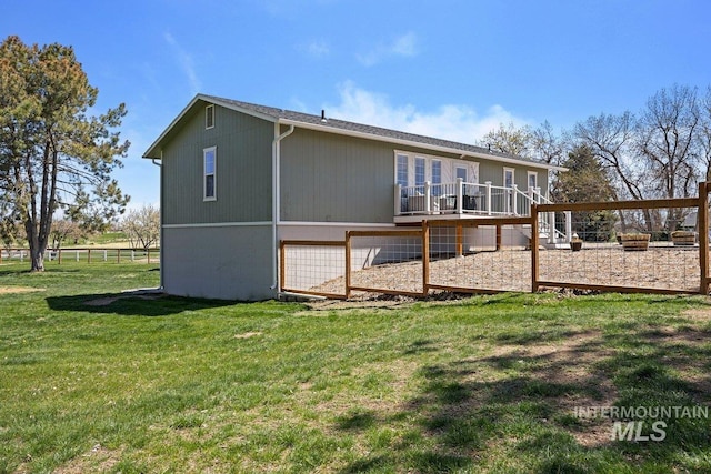 back of property with a wooden deck, a lawn, and fence