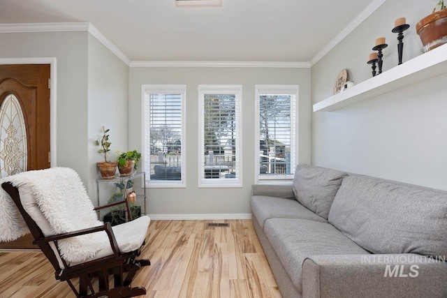 living area with baseboards, visible vents, light wood-style floors, and crown molding