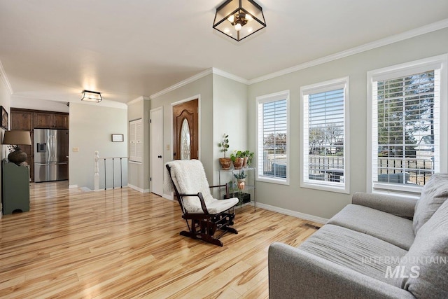 living area featuring light wood finished floors, plenty of natural light, baseboards, and crown molding