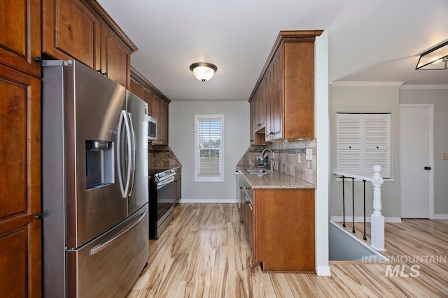 kitchen featuring backsplash, light wood-style floors, stainless steel appliances, and a sink