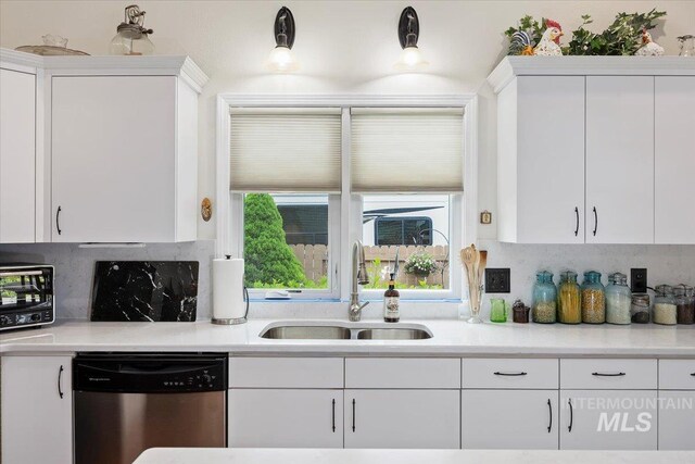 kitchen with dishwasher, a sink, and white cabinetry