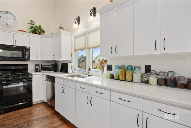 kitchen featuring black appliances, a sink, decorative backsplash, light countertops, and white cabinetry