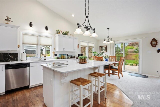 kitchen with dishwasher, a sink, light countertops, a kitchen island, and white cabinets