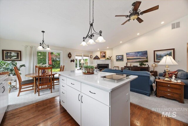 kitchen featuring a ceiling fan, lofted ceiling, pendant lighting, a center island, and a lit fireplace