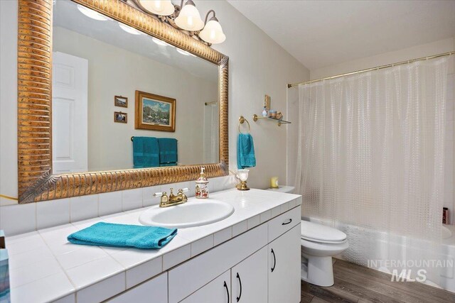 full bath featuring wood finished floors, toilet, vanity, and shower / bath combo with shower curtain