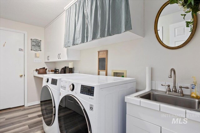 clothes washing area featuring independent washer and dryer, light wood finished floors, and cabinet space