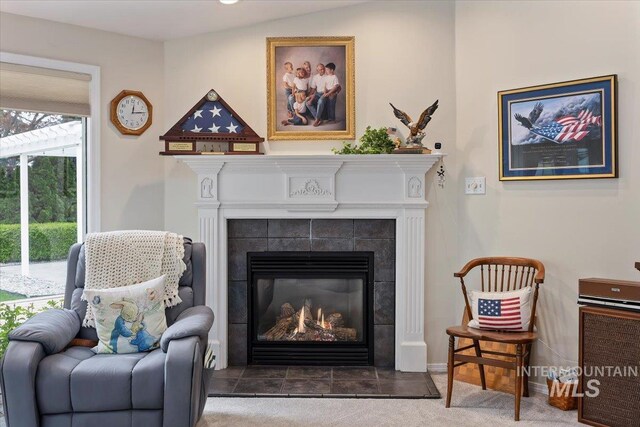 sitting room with a tiled fireplace, baseboards, and carpet floors