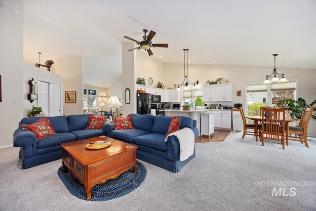living area featuring plenty of natural light, a ceiling fan, light colored carpet, and high vaulted ceiling