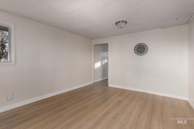 unfurnished room featuring baseboards, a textured ceiling, and wood finished floors