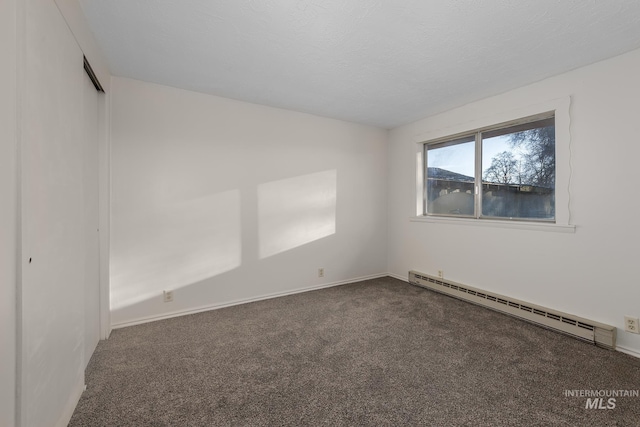 spare room featuring a textured ceiling, a baseboard heating unit, baseboards, and carpet floors