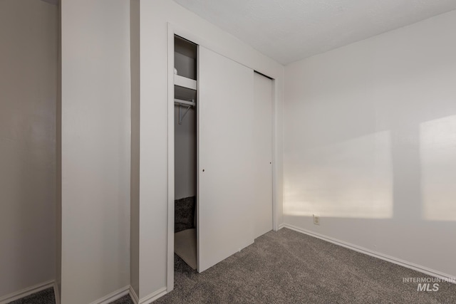 unfurnished bedroom with a closet and dark carpet