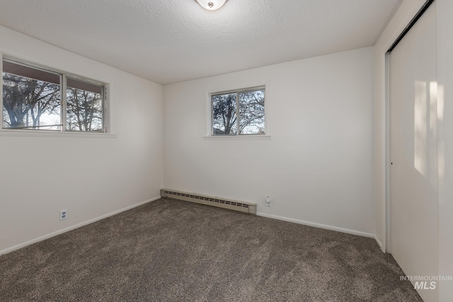 spare room with a wealth of natural light, carpet floors, a textured ceiling, and a baseboard radiator