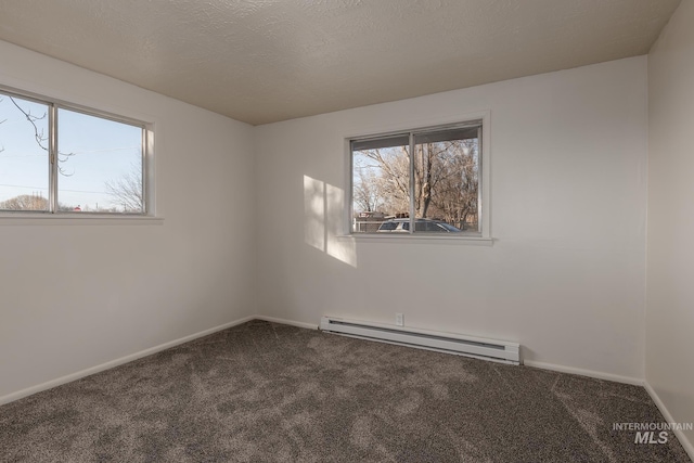 carpeted empty room featuring baseboard heating, a textured ceiling, and baseboards