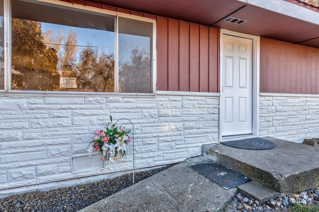 entrance to property featuring stone siding and visible vents