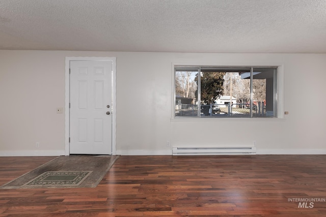 empty room with baseboard heating, a textured ceiling, baseboards, and wood finished floors