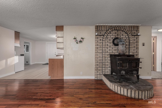 living room with a wood stove, wood finished floors, and a textured ceiling