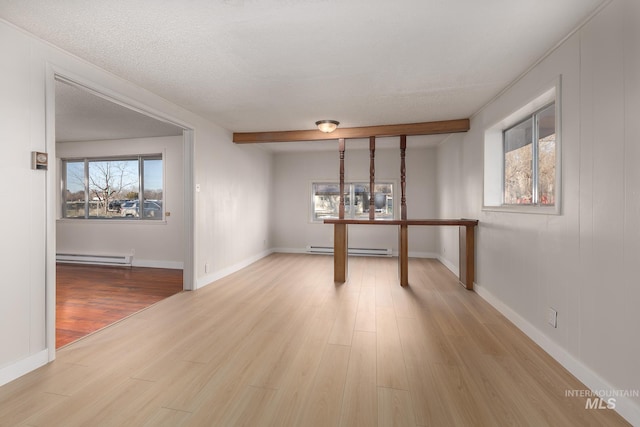 interior space featuring a baseboard heating unit, baseboards, beam ceiling, baseboard heating, and wood finished floors