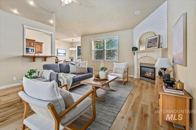 living room with light hardwood / wood-style floors, a textured ceiling, and a notable chandelier