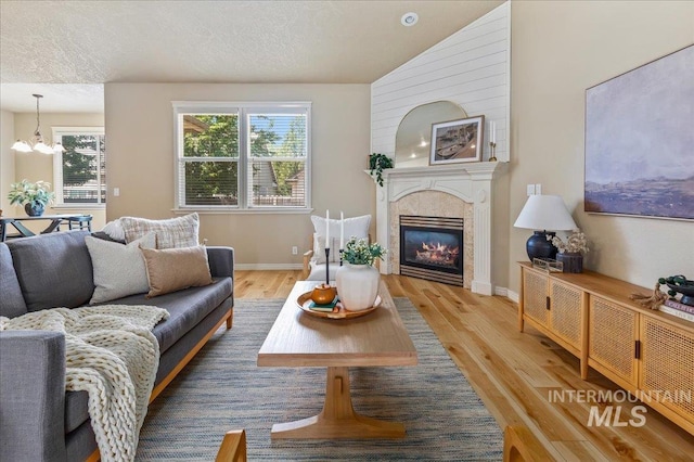 living room with a chandelier, a textured ceiling, and light hardwood / wood-style flooring