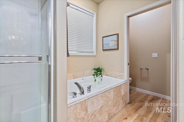 bathroom featuring wood-type flooring, shower with separate bathtub, and toilet