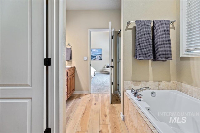 bathroom featuring tiled bath, vanity, and hardwood / wood-style flooring