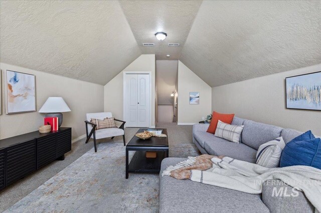 carpeted living room featuring a textured ceiling and lofted ceiling