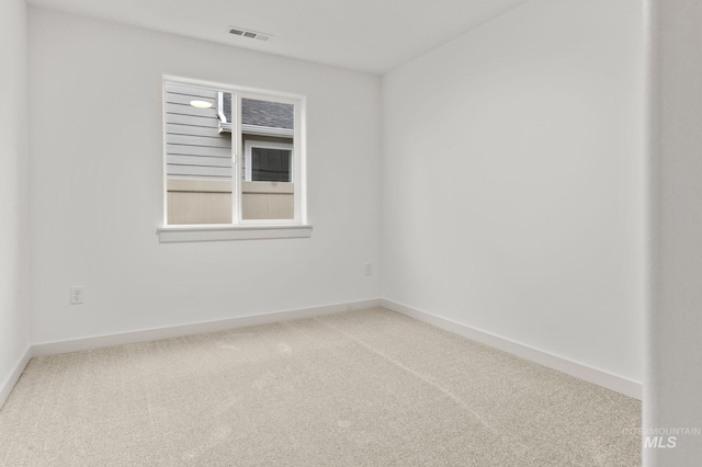 carpeted spare room featuring baseboards and visible vents