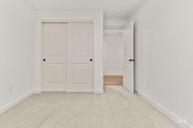 unfurnished bedroom featuring a closet, baseboards, and carpet flooring