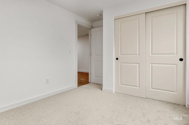 unfurnished bedroom featuring a closet, baseboards, and carpet flooring