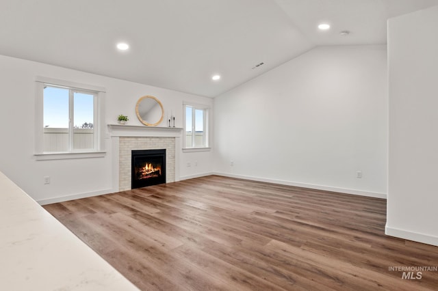 unfurnished living room featuring wood finished floors, recessed lighting, a brick fireplace, and lofted ceiling