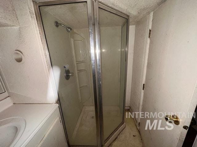 bathroom with a textured ceiling, vanity, and walk in shower