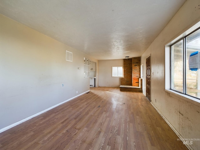 unfurnished living room featuring wood-type flooring and a wealth of natural light