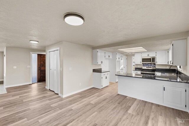 kitchen featuring white cabinetry, sink, kitchen peninsula, light hardwood / wood-style floors, and appliances with stainless steel finishes