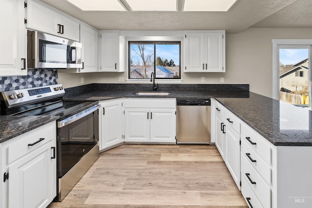 kitchen featuring stainless steel appliances, white cabinetry, a wealth of natural light, and sink