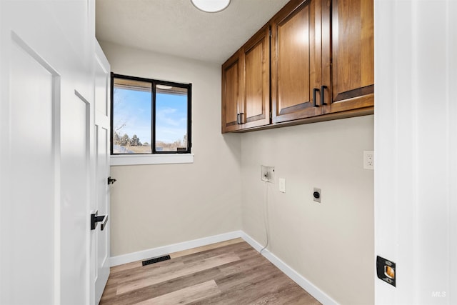 washroom featuring electric dryer hookup, cabinets, light wood-type flooring, and washer hookup