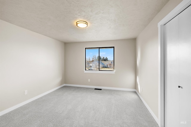 carpeted spare room with a textured ceiling