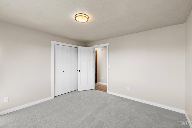 unfurnished bedroom with light carpet, a textured ceiling, and a closet