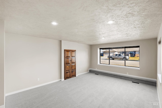 spare room featuring carpet and a textured ceiling