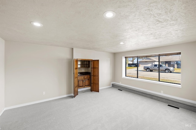 carpeted empty room featuring a textured ceiling