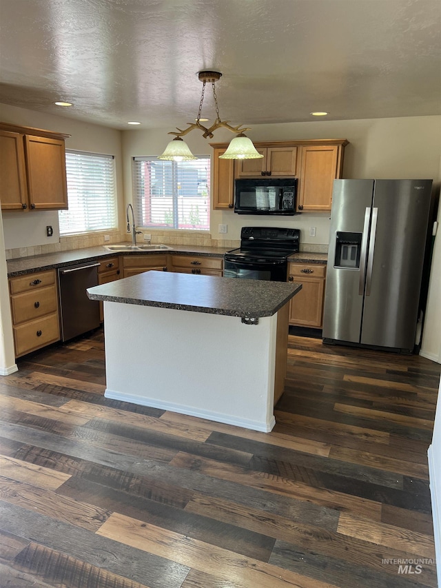 2059 Spring Creek Dr, Fruitland, ID 83619 - kitchen with black appliances, dark countertops, a center island, dark wood-type flooring, and pendant lighting