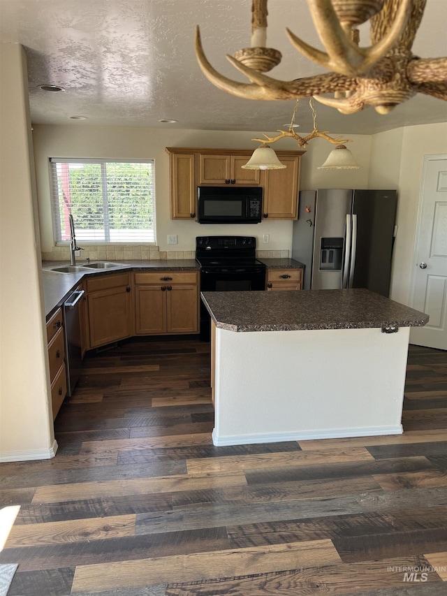 2059 Spring Creek Dr, Fruitland, ID 83619 - kitchen featuring black appliances, dark countertops, dark wood-style floors, a center island, and light brown cabinetry