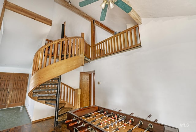 staircase with ceiling fan, beam ceiling, and high vaulted ceiling