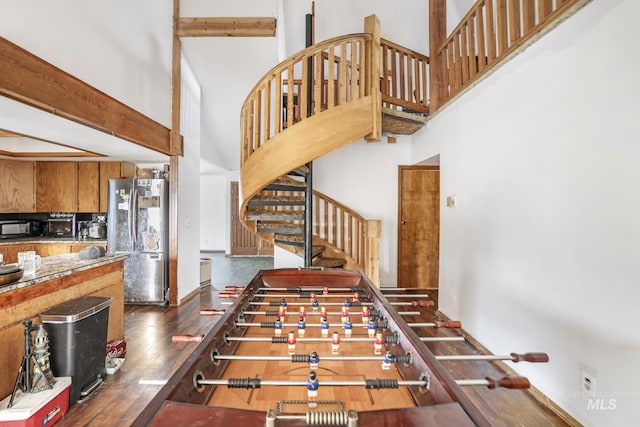 staircase featuring beamed ceiling, a high ceiling, and hardwood / wood-style flooring