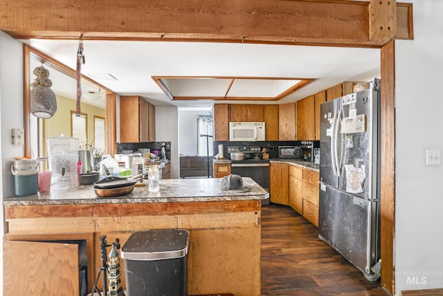 kitchen with stainless steel appliances, dark wood-type flooring, a peninsula, and brown cabinetry