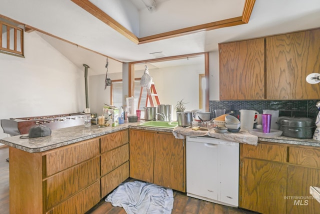 kitchen with dark wood-style floors, a peninsula, a sink, dishwasher, and backsplash